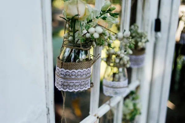 Pequenas decorações florais de casamento em estilo rústico pendurar em frascos decorados com saque e renda — Fotografia de Stock