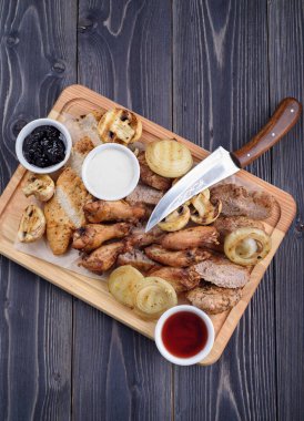 Kızarmış et dilimleri tavuk kanatları, jambon, bir ahşap tahta üzerinde soslu fileto