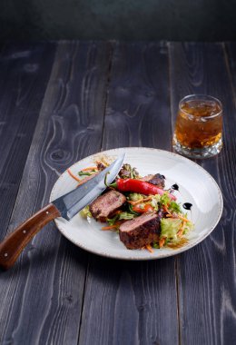 Tagliata biftek salata beyaz bir tabak ve bardak viski ile
