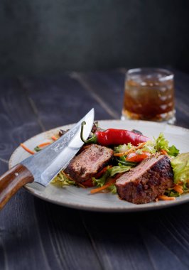 Tagliata biftek salata beyaz bir tabak ve bardak viski ile
