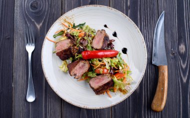 Dana beyaz bir tabak salata ile Tagliata 