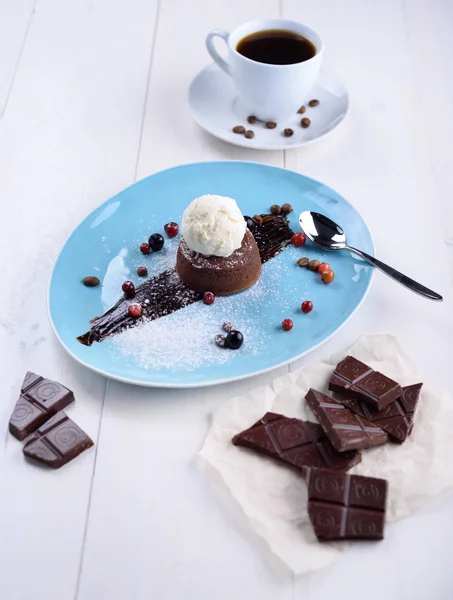 Шоколадная помадка с мороженым, кусочки шоколада и кофе на белом столе — стоковое фото