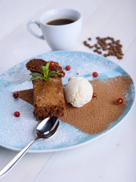 Шоколадное печенье с мороженым на синей тарелке рядом с чашкой кофе. Шоколадный торт с кофе — стоковое фото