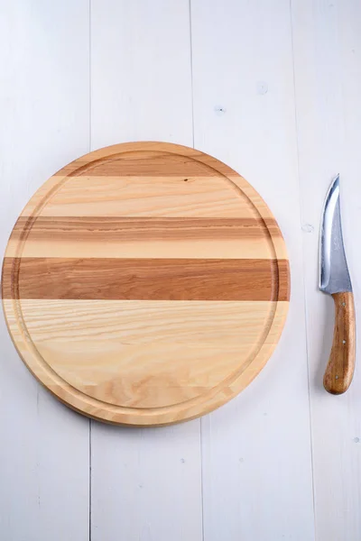 Ronde houten plank en mes op een witte achtergrond — Stockfoto