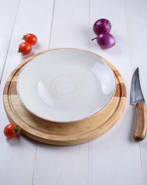 Empty white plate on a round wooden board — Stock Photo, Image