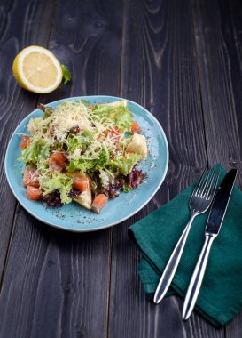 Sezar salatası somon ahşap bir masa üzerinde mavi bir plaka ile.