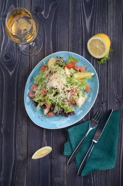 Salada de Caesar com salmão em uma chapa azul em uma mesa de madeira . — Fotografia de Stock