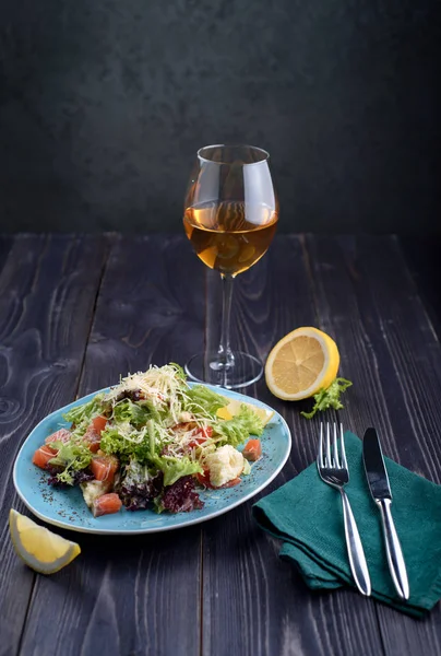 Salada de Caesar com salmão em uma chapa azul em uma mesa de madeira . — Fotografia de Stock