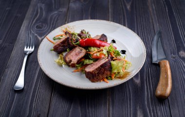 Dana beyaz bir tabak salata ile Tagliata 