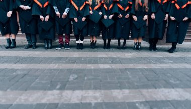 Mezunlar onların şapka elinde tutan. Mezunları ellerinde elbiseler ve şapka giyiyor. Grup öğrenci lisans önlük içinde 