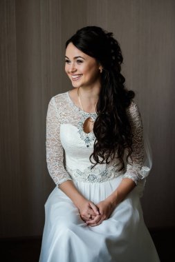 Oturma ve damat için kapalı bekliyor beyaz elbiseli güzel genç gelin. Zarif çekici genç esmer gelin kapalı bir gelinlikli poz. Sabah, Gelin