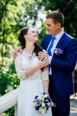 Gelin ve damat gülümse ve birbirlerine bakıyorlar. Gelin damat kucaklayan