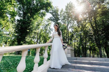 Buket el merdivenlerden aşağı yürüme ile giysi beyaz düğün gelin