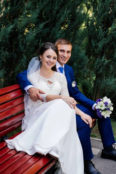 幸せな花嫁と新郎のベンチに座っていると屋外で 抱き締めるスペースにコピーします 結婚式のカップル — ストック写真