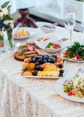 Akşam yemeği masada meyve ile plaka. Üzüm ve elma ve armut masanın üzerinde beyaz bir tabak içinde parçalar