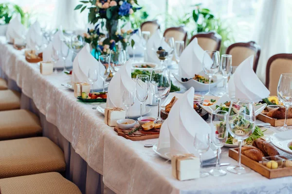 Table setting. Table served for wedding banquet, close up view. White napkin on a white empty plate on a dining table