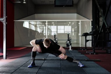 Genç adam eğitim önce kasları hazırlanıyor. Spor salonunda egzersiz kas atlet. Germe adam uygun. Isınma-up profesyonel sporcu. Tam vücut uzunluğu portre