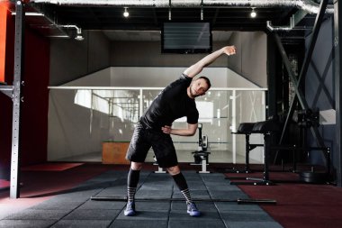 Genç adam eğitim önce kasları hazırlanıyor. Spor salonunda egzersiz kas atlet. Germe adam uygun. Isınma-up profesyonel sporcu. Tam vücut uzunluğu portre