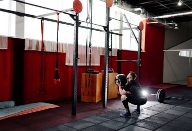 Kaslı adam egzersiz jimnastik salonu sağlık topu ile yapmak. Genç adam ağır ağırlıklı topu ile çalışma dışarı üst vücut egzersiz yaparak