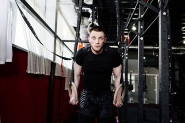 Atlet kasları halkalar üzerinde çalışıyor. Spor salonu pull UPS Jimnastik halkalar ile çalışan adam. CrossFit çekirdek egzersiz