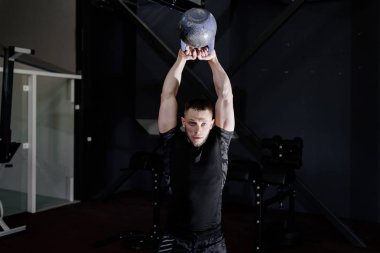 Genç adam spor salonunda su ısıtıcısı çan ile çalışma dışarı içinde sakallı. Kettlebell eğitim salonunda