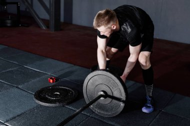 Sakallı adam ağırlık koyarak spor salonunda açık bar. Egzersiz halter ile hazırlanıyor. Vücut geliştirmeci ağırlıkları üzerinde halter koyar.