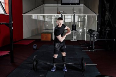 Genç adam onun pazı spor salonunda gösterilen siyah t-shirt giymiş çığlık. Spor salonunda poz ve onun pazı gösterilen süre kameraya bakarak adam