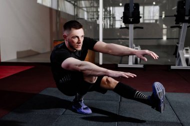 Spor salonunda bir bacak üzerinde tabanca yapan kas sakallı erkek ağız kavgası