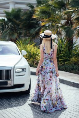 Çiçek desenli ve hasır şapka ile bir elbiseli güzel genç kadın beyaz araba gider