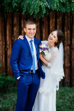Gelin Damat kucaklar. Gelin ve damat ahşap duvar günlüğündeki Park yakınındaki. Evlilik çift, düğün günü aşık