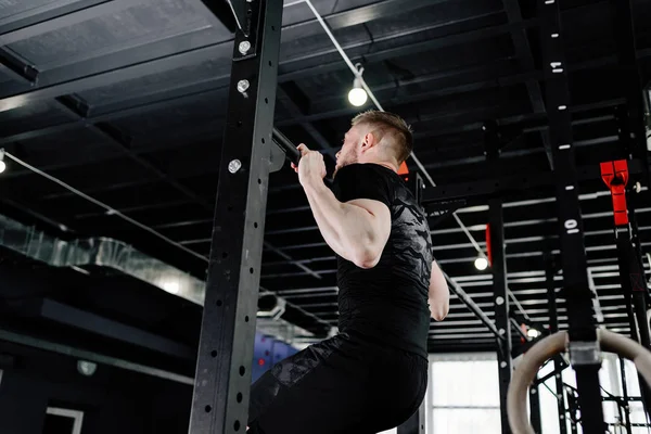 Muscular bearded man training his biceps and back in gym. Pull-ups. Workout lifestyle concept