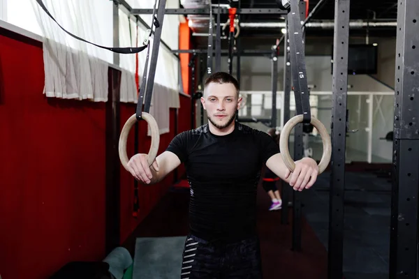 Athlete working out his muscles on rings. Man working out in gym pull ups with gymnastic rings