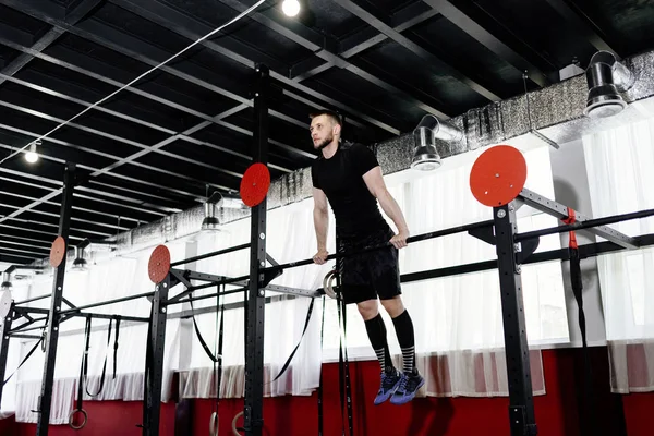 Young man exercising on horizontal bar in the gym. Male adult working out triceps and biceps on horizontal bar