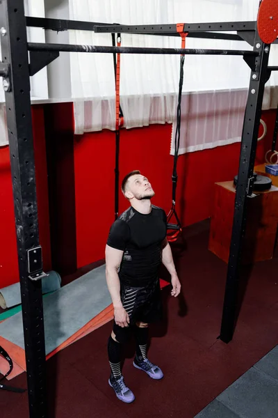 Muscular bearded man preparing to training his biceps and back in gym. Pull-ups. Workout lifestyle concept