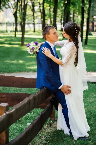 Bride and groom hugs in the park. Groom embraces the bride. Wedding couple in love at wedding day