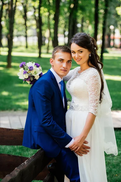 Abraços de noiva e noivo no parque. O noivo abraça a noiva. Casamento casal apaixonado no dia do casamento — Fotografia de Stock