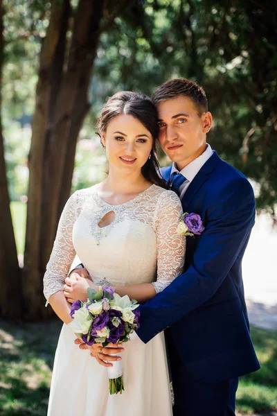 Abraços de noiva e noivo no parque. O noivo abraça a noiva. Casamento casal apaixonado no dia do casamento — Fotografia de Stock