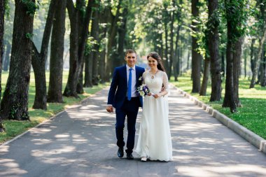 Gelin ve damat merdivenlerden parkta yürürken. Damat gelini kucaklar. Evlilik çift, düğün günü aşık