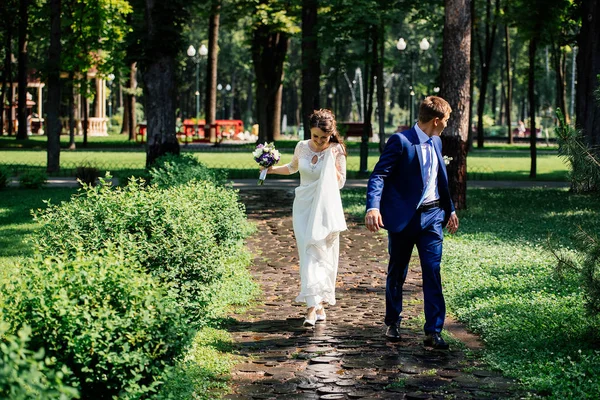 Braut und Bräutigam beim Spaziergang im Park. Hochzeitspaar verliebt am Hochzeitstag — Stockfoto