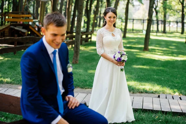 Linda noiva jovem com buquê de casamento com noivo em borrão na frente dela. Casamento casal apaixonado no dia do casamento — Fotografia de Stock