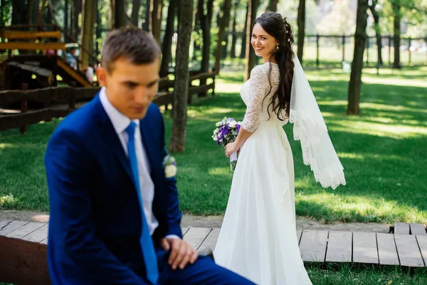 Linda noiva jovem com buquê de casamento com noivo em borrão na frente dela. Casamento casal apaixonado no dia do casamento — Fotografia de Stock