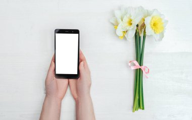 Beyaz smartphone ekran beyaz arka plan üzerinde narcissus oluşan yakınındaki kızın elinde. Teknoloji ve iletişim kavramı 