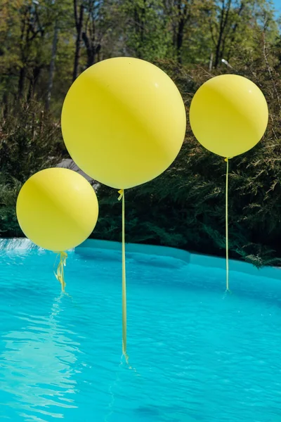 Pool with big yellow balloons outdoor. Poolside party. The balloons on water. Decorations for wedding ceremony by the pool with blue water