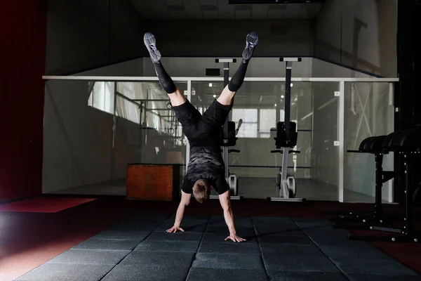 Athlete walking on his hands standing upside down in gym. Crossfit training. Workout lifestyle concept.  Full body length portrait