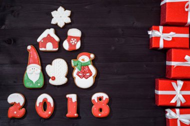 Zencefilli kurabiye ve ahşap zemin, kopya alanı üzerine kırmızı hediyeler yapılan köknar ağacı ile Noel arka plan. Yeni yıl 2018 kartpostal gingerbread kardan adam, Noel Baba, kar tanesi, house, mitten, çorap ile