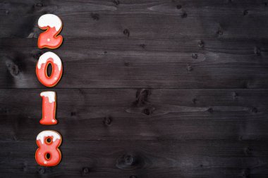 Mutlu yeni yıl 2018 işareti simgesi kopya alanı koyu ahşap arka plan üzerinde kırmızı ve beyaz gingerbread çerezleri üzerinden. Üstten Görünüm, düz yatıyordu