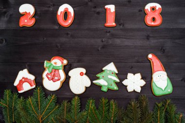 Mutlu yeni yıl 2018 işareti simgesi kopya alanı koyu ahşap arka plan üzerinde kırmızı ve beyaz gingerbread çerezleri üzerinden. Üstten Görünüm, düz yatıyordu. Noel kurabiyeleri ve köknar ağacı dalları sınır, boş alan