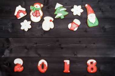 Mutlu yeni yıl 2018 işareti simgesi kopya alanı koyu ahşap arka plan üzerinde kırmızı ve beyaz gingerbread çerezleri üzerinden. Üstten Görünüm, düz yatıyordu. Noel çerezleri sınır, boş alan. Noel arka plan