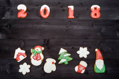 Mutlu yeni yıl 2018 işareti simgesi kopya alanı koyu ahşap arka plan üzerinde kırmızı ve beyaz gingerbread çerezleri üzerinden. Üstten Görünüm, düz yatıyordu. Noel çerezleri sınır, boş alan. Noel arka plan