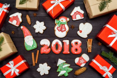 Mutlu yeni yıl 2018 işareti sembolü, kırmızı ve beyaz gingerbread çerezleri ve koyu ahşap arka plan üzerinde hediye kutuları. Üstten Görünüm, düz yatıyordu. Noel kurabiyeleri, Noel kurabiyeleri, santa, kardan adam, kar tanesi